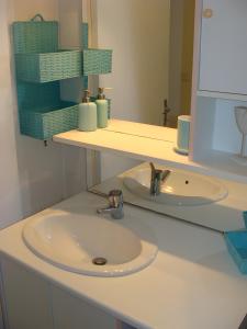 een badkamermeubel met een wastafel en een spiegel bij Maison Les Volets Bleus Binic in Lantic