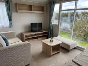 a living room with a tv and a couch and a table at Merryfield and Sandfields in Chapel Saint Leonards