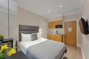 a small bedroom with a bed and a kitchen at Cleveland Residences Kensington in London