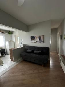 a living room with a black couch and a kitchen at Frente ao mar, conforto e paz apto 12 in Praia Grande