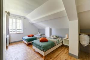two beds in a bedroom with white walls and wood floors at Le Vert Bocage - Avec Jardin in Rouvroy-sur-Serre