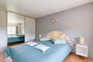 a bedroom with a blue bed and a mirror at L'Orée du Bois - Avec Jardin in Rouvroy-sur-Serre