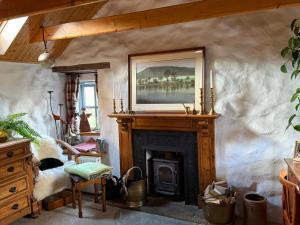 a living room with a fireplace and a painting on the wall at Allt Mor Cottage in Milovaig +1 photo