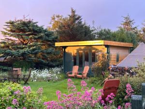 a garden with a cabin with chairs and flowers at Allt Mor Cottage in Milovaig