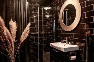 ヘガネスにあるFalknästetの黒いタイル張りのバスルーム(シンク、鏡付)