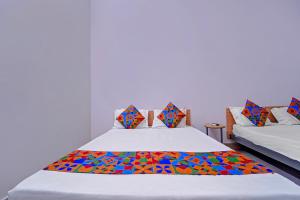 Un dormitorio con dos camas con almohadas de colores. en Via Lishikaas Inn, en Tākalghāt