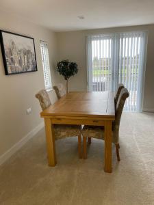 a wooden dining room table with chairs in a room at Three bedroom cabin with rural views and hot tub in Algarkirk