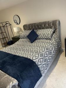 a bed with a black and white comforter and pillows at Three bedroom cabin with rural views and hot tub in Algarkirk