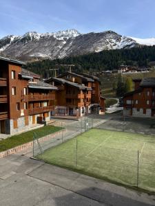 a tennis court in front of some buildings with mountains at Les Traverses 18 in Valmorel