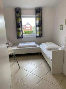 twee bedden in een kamer met een raam bij Meeresbrise 14 in Wangerland