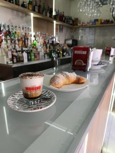 a cup of coffee and a croissant on a counter at AparthouseRisorgimento BORBONE in Frattamaggiore +7 photos