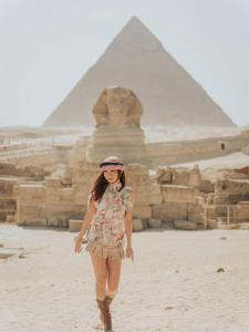 una mujer caminando delante de las pirámides en ArQa pyramids Hotel, en El Cairo