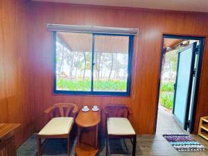 comedor con mesa, 2 sillas y ventana en Khu Camping & Homestay Ven Biển, en Ấp Phước Tĩnh