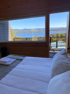 1 dormitorio con 1 cama grande y vistas al agua en Huillín Lodge, en Huillinco