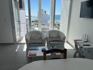 two chairs and a table in a room with a large window at Ninfas Plaza in Puerto Madryn