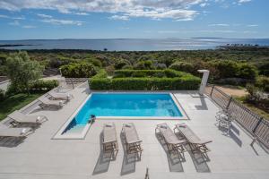 a villa with a swimming pool and chairs at Villas Royal III in Novalja