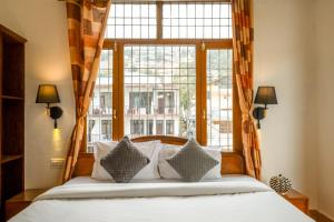 a bedroom with a bed and a large window at Artllers at Vicctoria House, All Mountain View rooms with Free Parking in McLeod Ganj