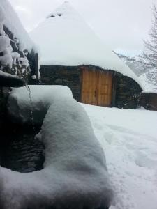 una pila de nieve delante de una casa en Palloza Baltasar, en Castelo