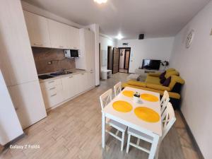 a kitchen and a living room with a white table and chairs at Luxury Seaside Apartment Alezzi Green Swimming Pool in Mamaia Nord