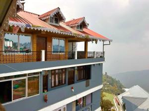 a house with a red roof and a balcony at Norbu T Homestay in Darjeeling