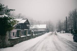 una calle cubierta de nieve con una casa y una carretera en Hanul Vanatorului, en Gureni 54 fotos más