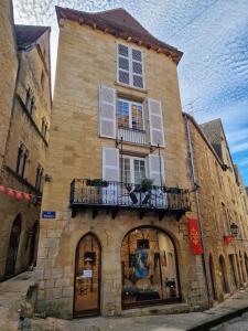a large brick building with a balcony and windows at Les Flamboyants in Sarlat-la-Canéda