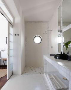a white bathroom with a sink and a mirror at Axminster House in Muizenberg