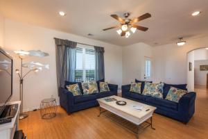a living room with two blue couches and a ceiling fan at Sandy Hook in Galveston