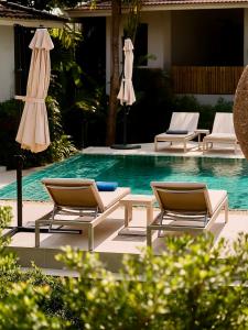 a group of chairs and umbrellas next to a swimming pool at Tulum Villa Resort Koh Samui in Bophut