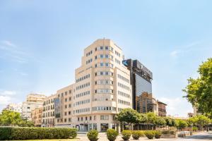 a tall white building with trees in front of it at Hotel Palma Avenidas in Palma de Mallorca