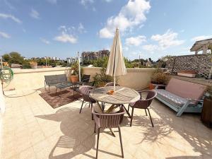 a patio with a table and chairs and an umbrella at Spacious 3BD Penthouse with Rooftop & Parking in Ra‘ananna