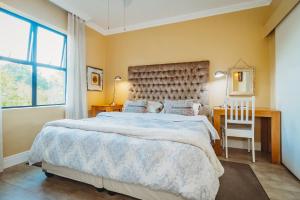 a bedroom with a large bed and a desk and window at 17onWellington Apartments in George