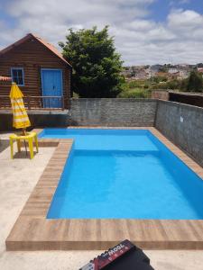 a blue swimming pool with a yellow chair and a house at Casa refúgio in Ibicoara