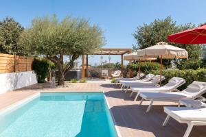 una piscina con tumbonas y sombrillas junto a en Terpsis Pool Villa, en Rodas