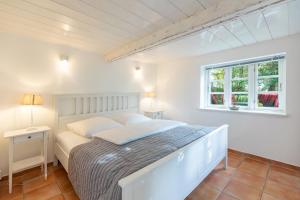 a white bedroom with a bed and a window at Reethus Humptrup in Humptrup