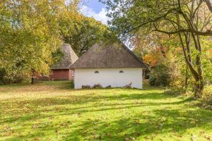 a white building with a thatched roof in a field at Reethus Humptrup in Humptrup