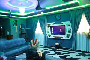 a living room with a blue couch and a tv at Erliz villa in Kumasi