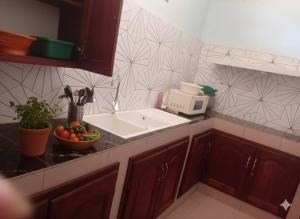 Abomey-CalaviAT Home的厨房配有水槽和一碗水果