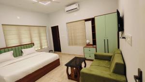 a bedroom with a bed and a green couch at Oasia Resort in Kannur