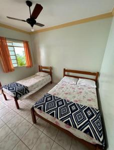 a bedroom with two beds and a ceiling fan at Pousada Rezende in Caldas Novas