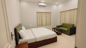 a bedroom with a bed and a green chair at Oasia Resort in Kannur