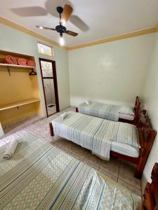 a bedroom with two beds and a ceiling fan at Pousada Rezende in Caldas Novas