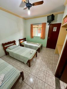 a room with two beds and a ceiling fan at Pousada Rezende in Caldas Novas