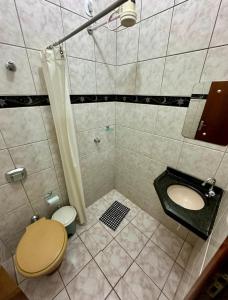 a bathroom with a shower and a toilet and a sink at Pousada Rezende in Caldas Novas