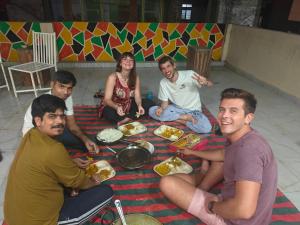 a group of people sitting around a table eating food at The Pink Nest - Backpackers Abode in Jaipur