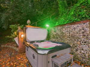 a bath tub with a tv on a brick wall at 19th Century Manor with Hot Tub in Lewes