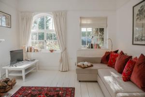a living room with a couch and a table and windows at Butley Priory Cottage in Woodbridge