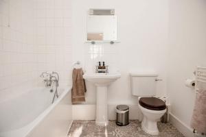 a bathroom with a toilet and a sink and a bath tub at Butley Priory Cottage in Woodbridge +24 photos