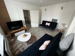 a living room with a blue couch and a tv at appartement au premier étage in Thaon-les-Vosges