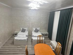 a room with two beds and a table and chairs at Pearl House in Muruntau